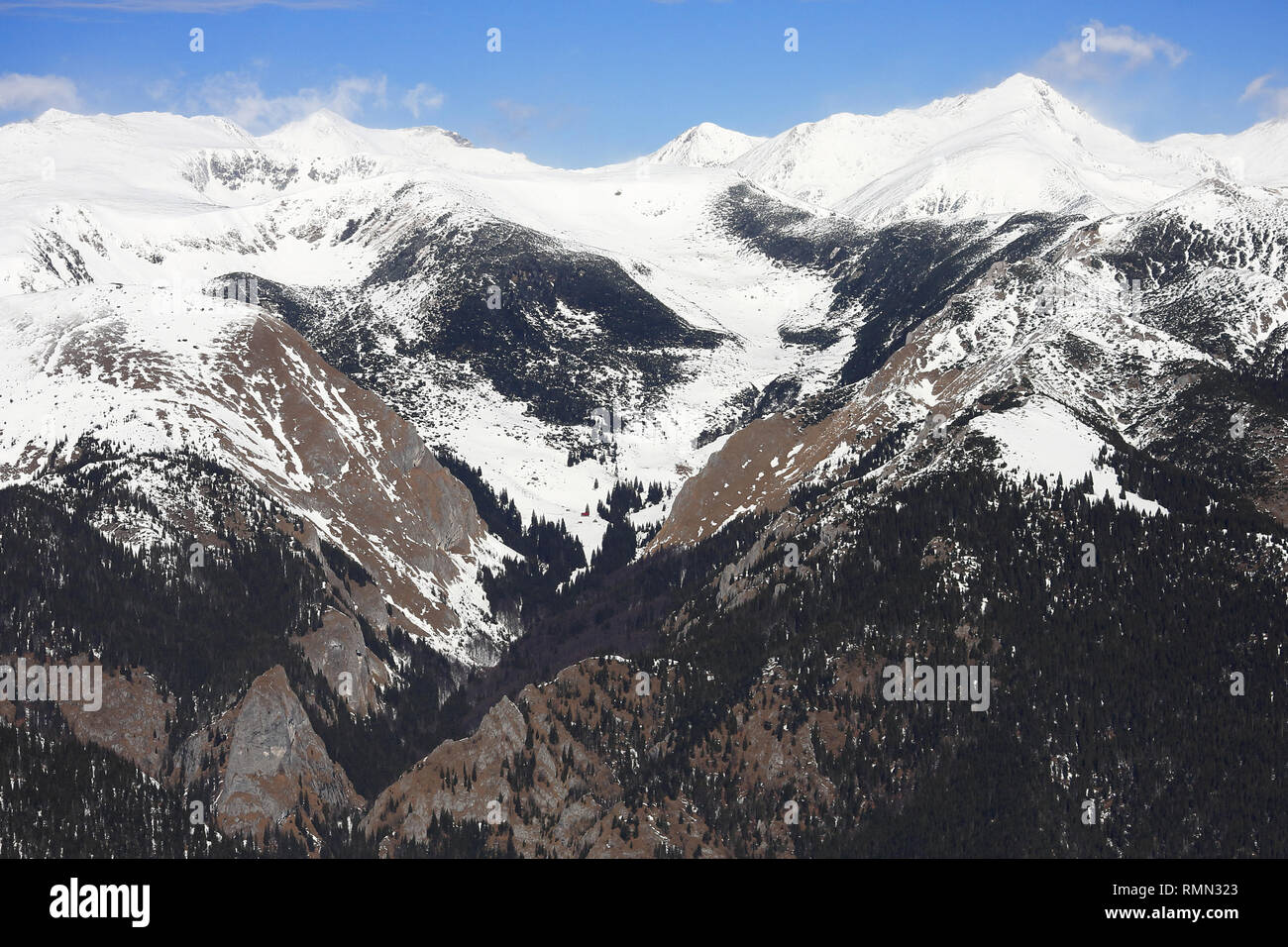 Una bellissima vista di alta quota cime coperte di neve e una bella valle in mezzo a partire tra due creste rocciose con assenza di neve a sinistra e contin Foto Stock