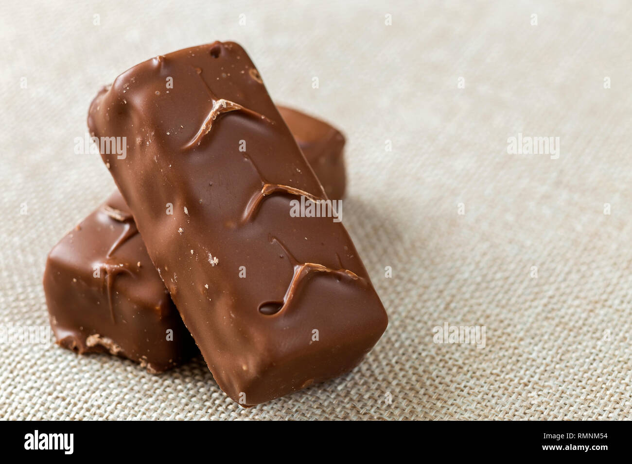 Due isolati isolato di color marrone scuro caramella di cioccolato snickers bar sulla luce tela panno spazio copia dello sfondo. Il cibo gustoso e nutriente merenda, concetto. Foto Stock