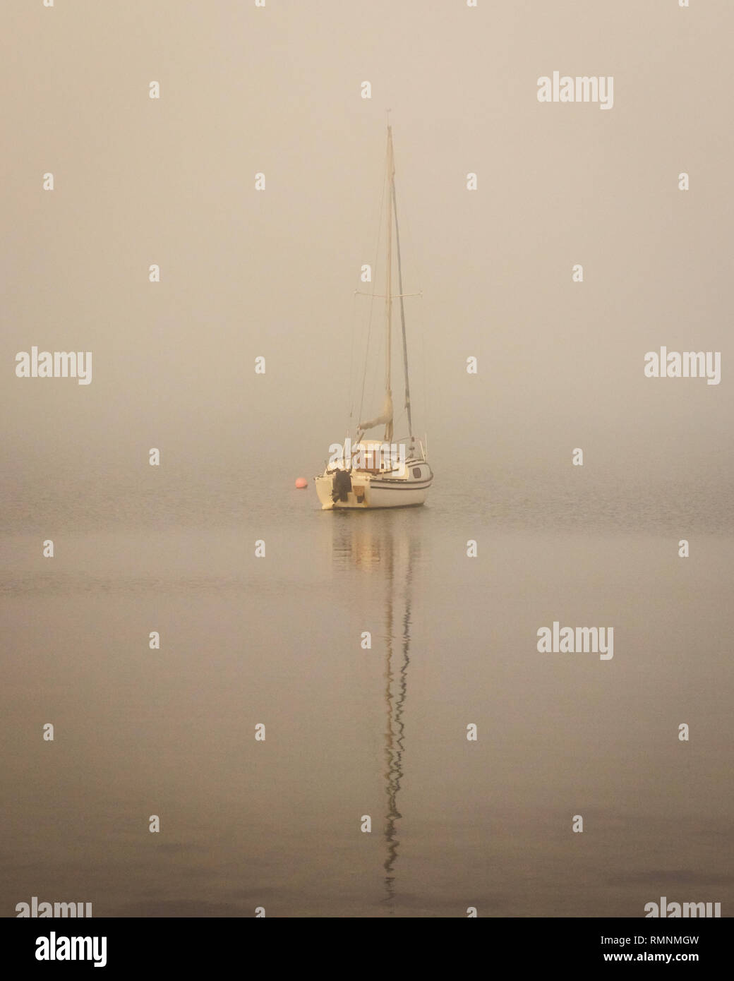 Imbarcazione a vela nella nebbia con riflessi in acqua calma, Tipner, Portsmouth, Hampshire, Regno Unito Foto Stock