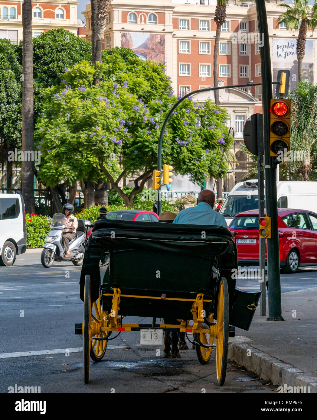 Tradizionale turistico carrozza con autista in attesa di clienti al semaforo rosso, Malaga, Andalusia, Spagna Foto Stock
