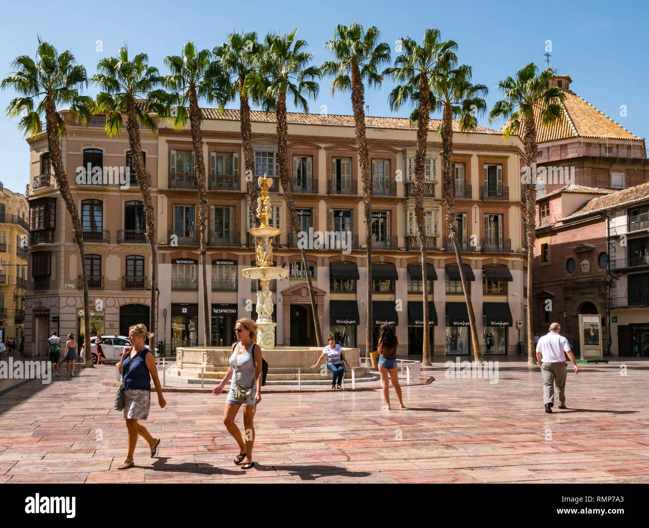 Edifici vecchi e fontana in marmo di Genova, con donne che indossano pantaloncini a piedi nella Plaza de la Constitucion o Piazza della Costituzione, Andalusia, Spagna Foto Stock