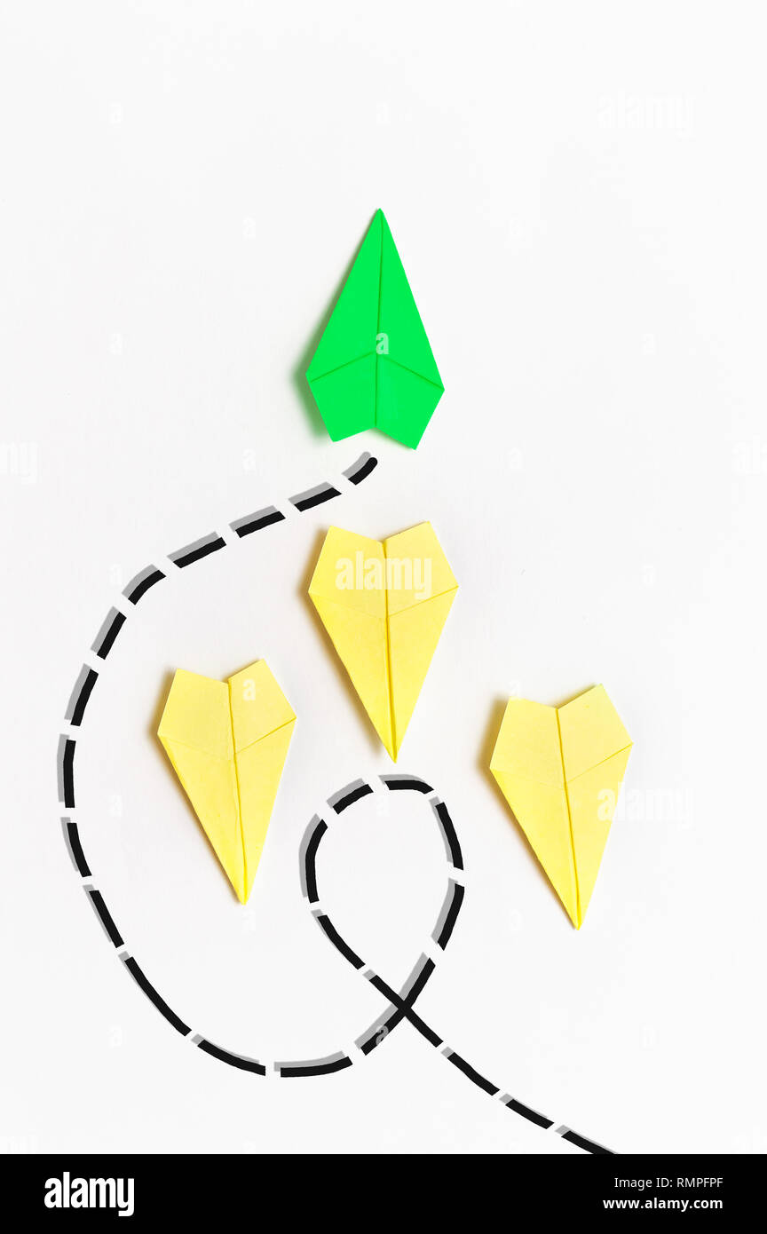 Concetto di differenziazione - Verde aeroplano di carta di andare in un'altra direzione rispetto a giallo aeroplani Foto Stock