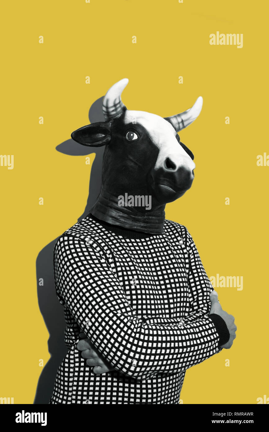 Giovane uomo caucasico con una maschera di vacca, in bianco e nero su sfondo giallo con un po' di spazio vuoto sulla parte superiore Foto Stock