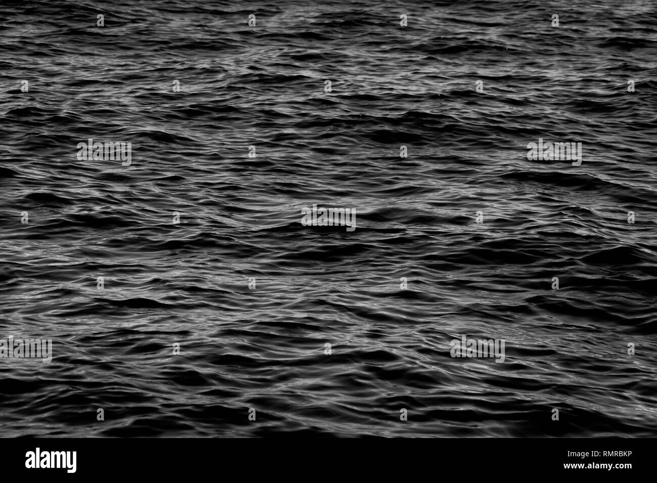 Dark in bianco e nero di acqua di mare con onde calme texture di sfondo o Foto Stock