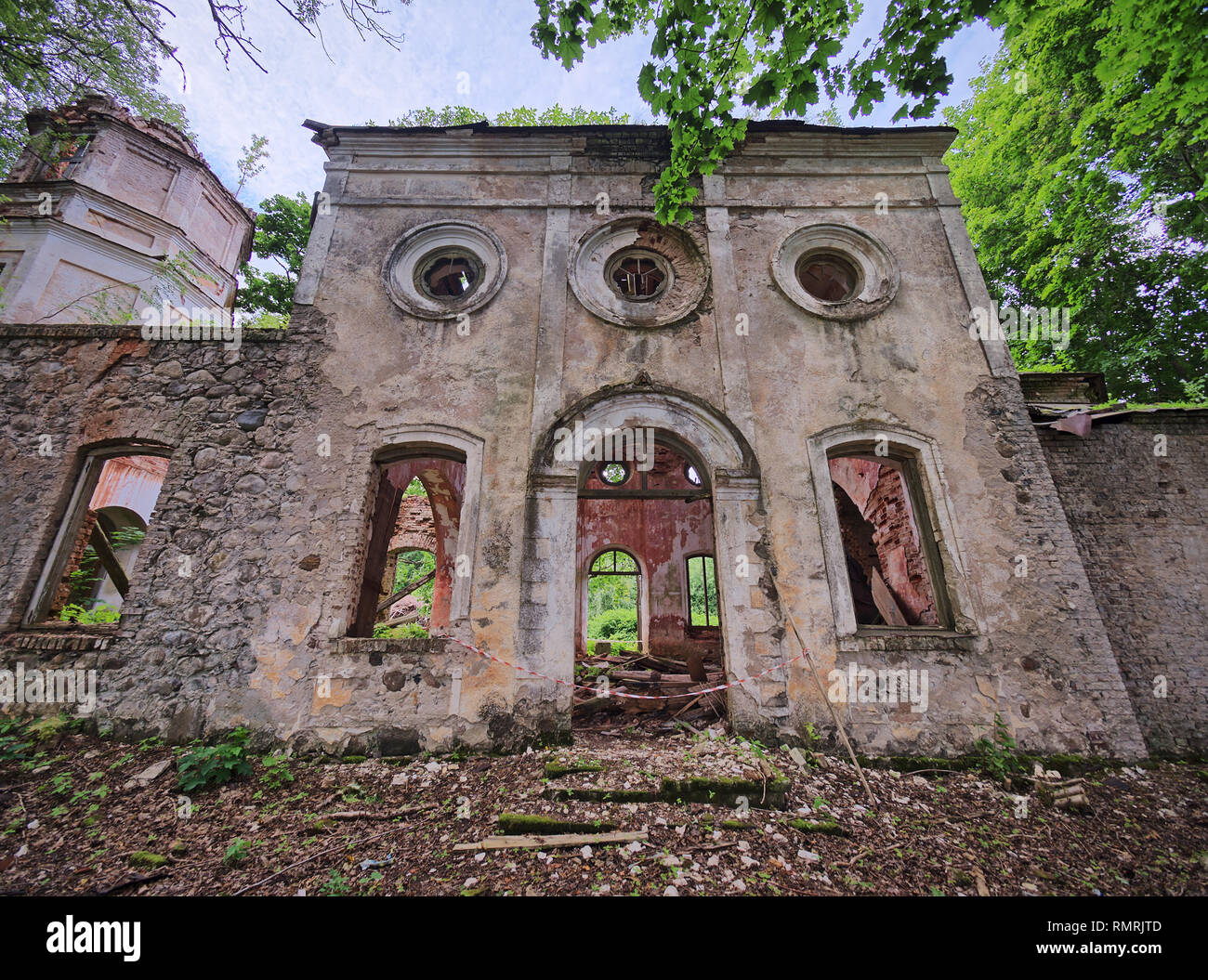 Vecchio abbandonato la Chiesa di San Nicola ruderi in Estonia. Il lussureggiante fogliame degli alberi e foreste che coprono la bellezza di questo antico edificio rovinato. Foto Stock