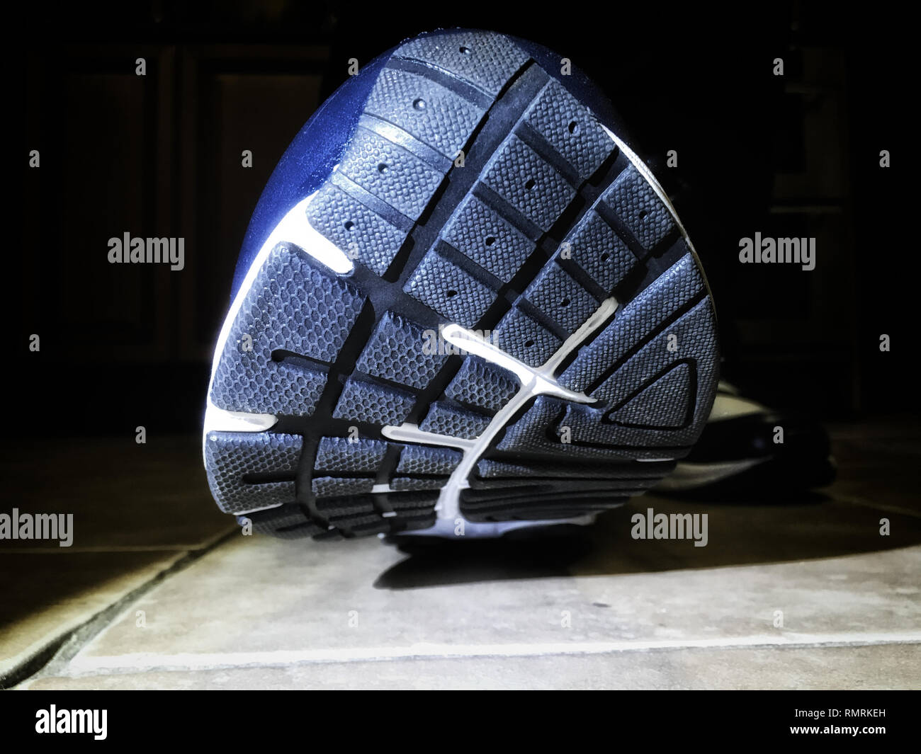 Una calzatura con una suola di gomma sta per sbarcare su polv. Mostra il al di sotto di un trainer. Foto Stock