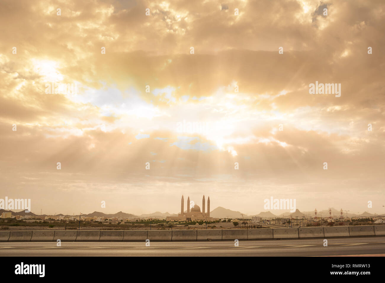 Panorama della città di Nizwa e la moschea con cielo nuvoloso e raggi di luce (Oman) Foto Stock