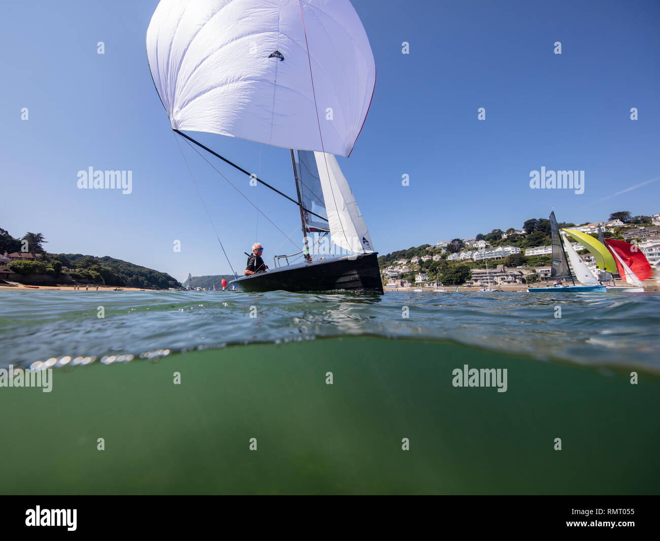 Uno yacht a vela durante il passato della città di Salcombe regata sotto un bel cielo blu. Foto Stock