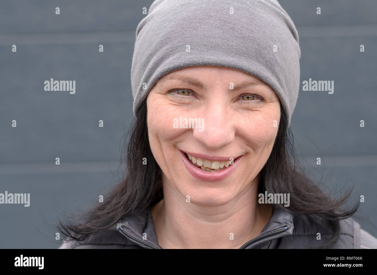 Ritratto di sorridere donna di mezza età che indossa grigio beanie hat. Foto Stock