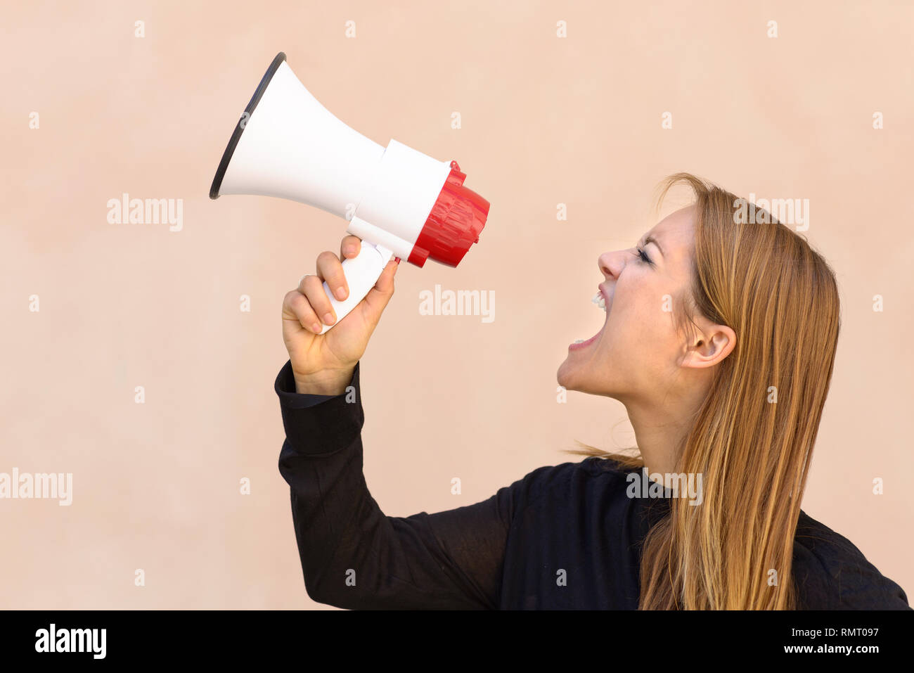 Arrabbiato donna urlare in un megafono o bullhorn in una vista profilo concettuale del una protesta, dimostrazione e rancori di aerazione Foto Stock