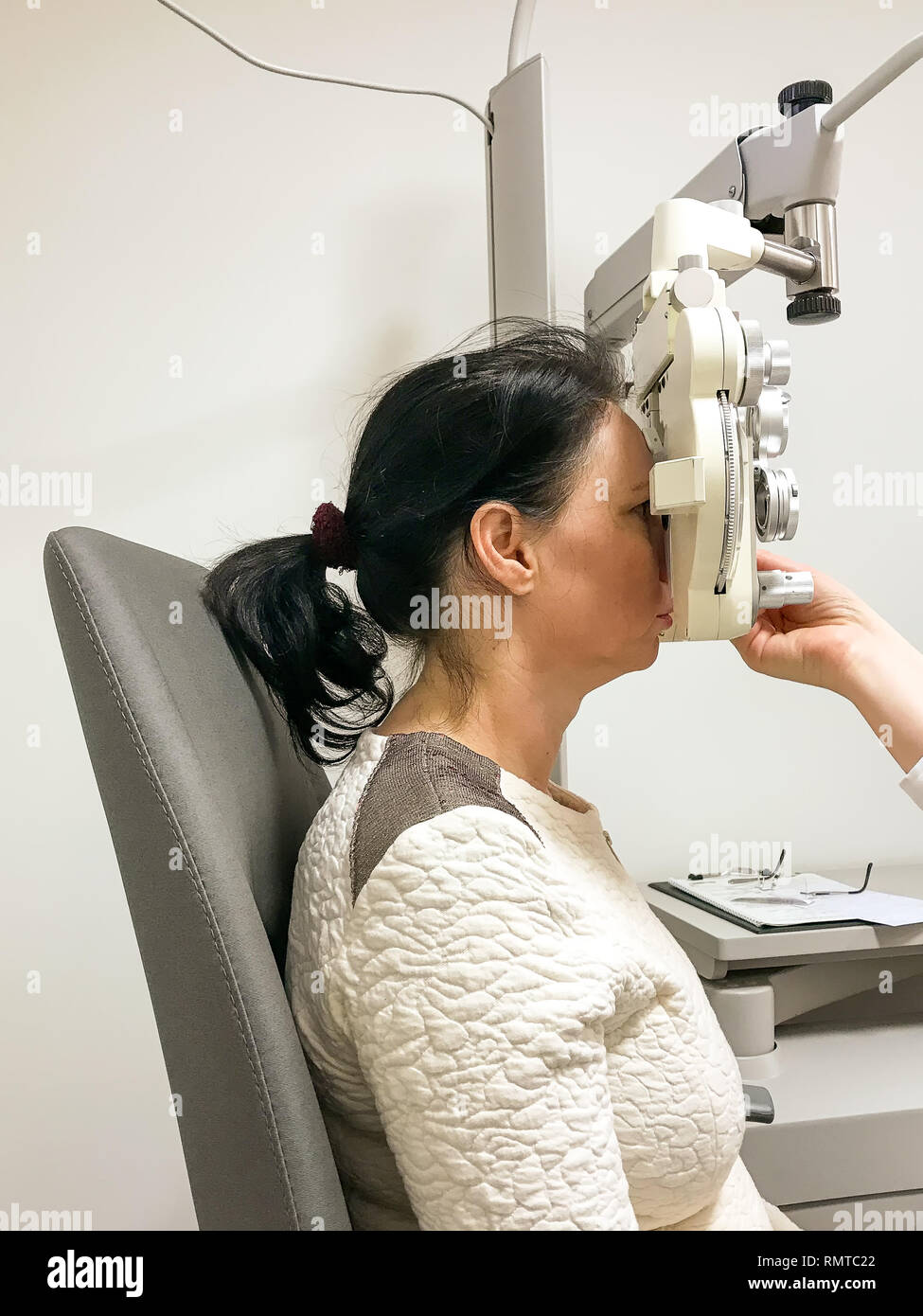 Donna subendo un occhio di test a un test all'ottico optometrista il sistema Acuity dei suoi occhi per la prescrizione di lenti correttive per occhiali Foto Stock
