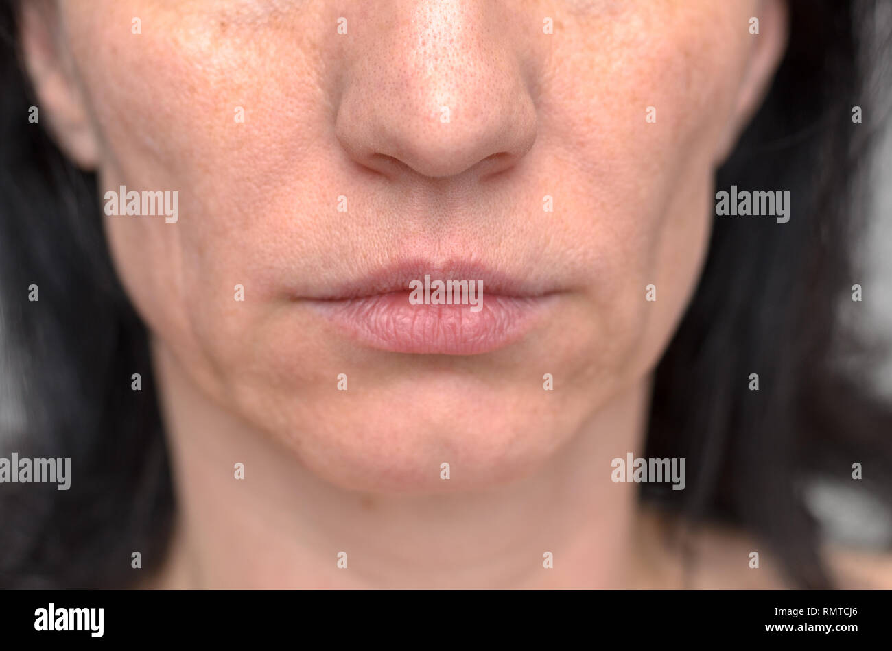 Primo piano sulla bocca di mezza età brunette donna con la sua bocca chiusa e una espressione seria Foto Stock