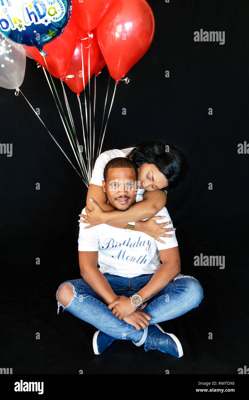 Paio di jeans blu con palloncini rossi che festeggiano il loro compleanno insieme allegramente Foto Stock