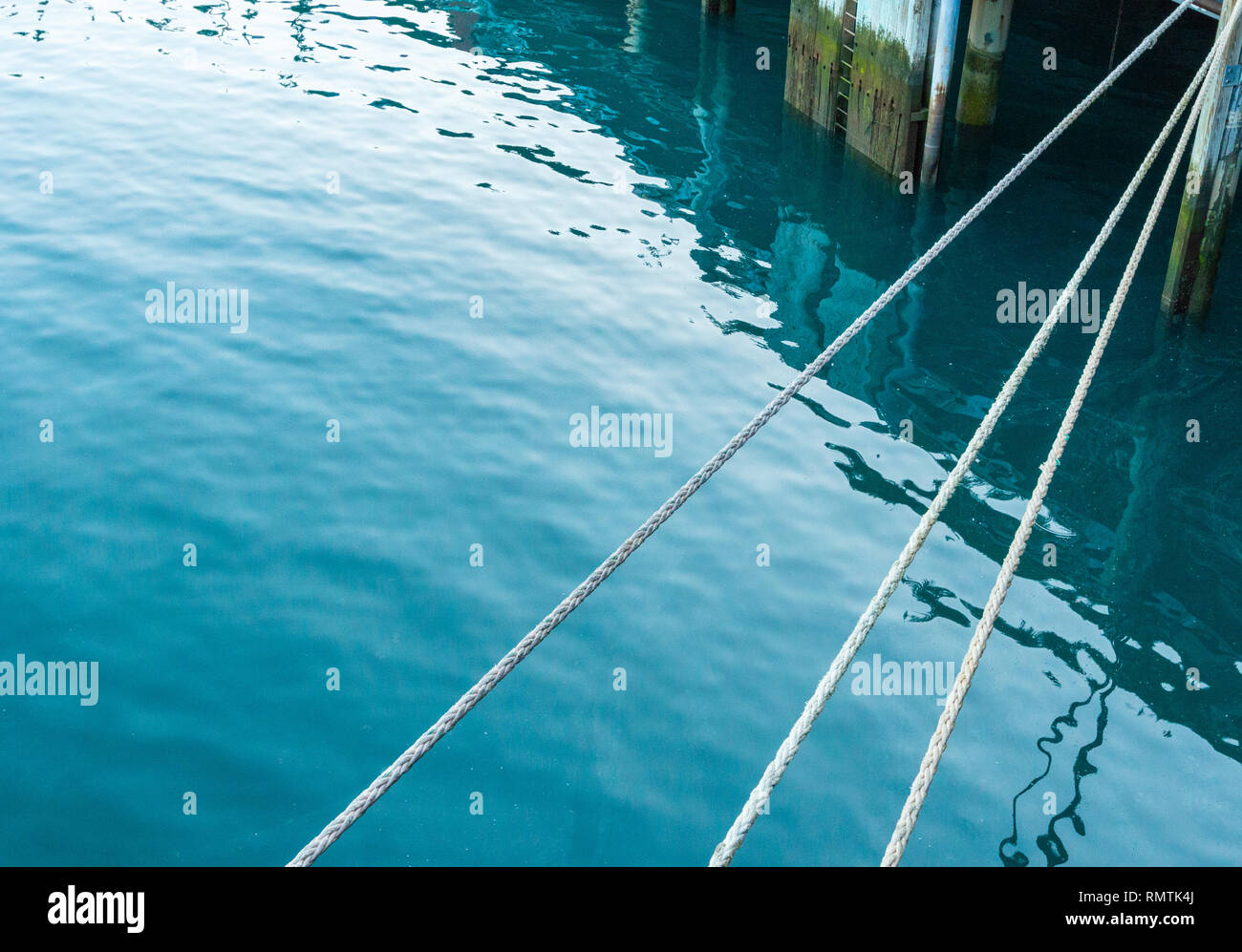 Tre corda linee di ormeggio attaccato al molo in legno a poppa della nave da crociera. Foto Stock