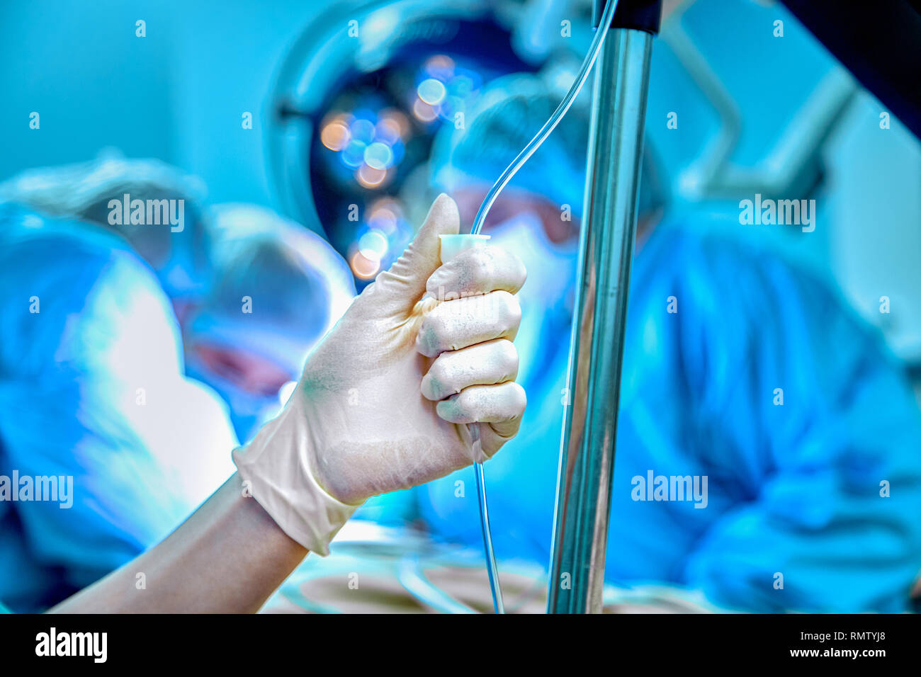 Dropper in vena di close-up su uno sfondo del funzionamento chirurgico. Medico donna in guanti sterili imposta il gocciolare Foto Stock