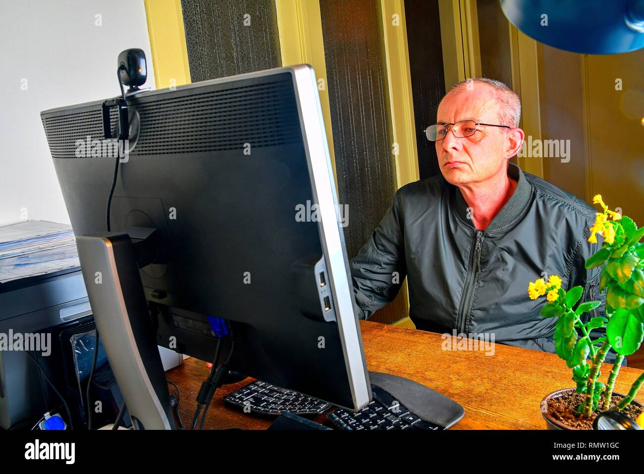 Uomo di mezza età con gli occhiali seduto alla scrivania. Uomo maturo che utilizzano personal computer. Concetto senior. Uomo che lavora in ufficio Foto Stock
