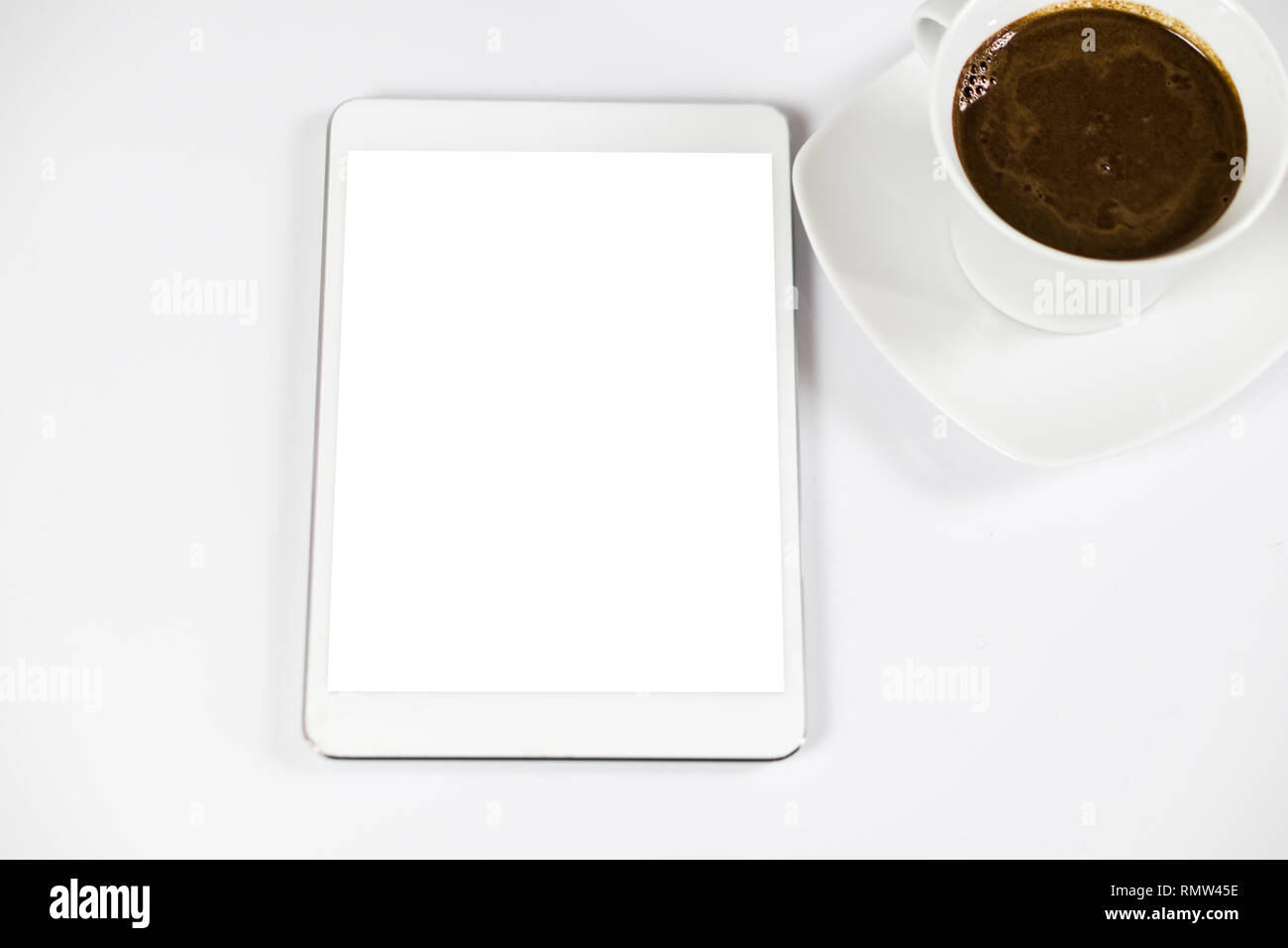 Computer tablet con bianco schermata vuota accanto al caffè. Il tablet è sul tavolo bianco. Vista dall'alto. Close-up. Foto Stock