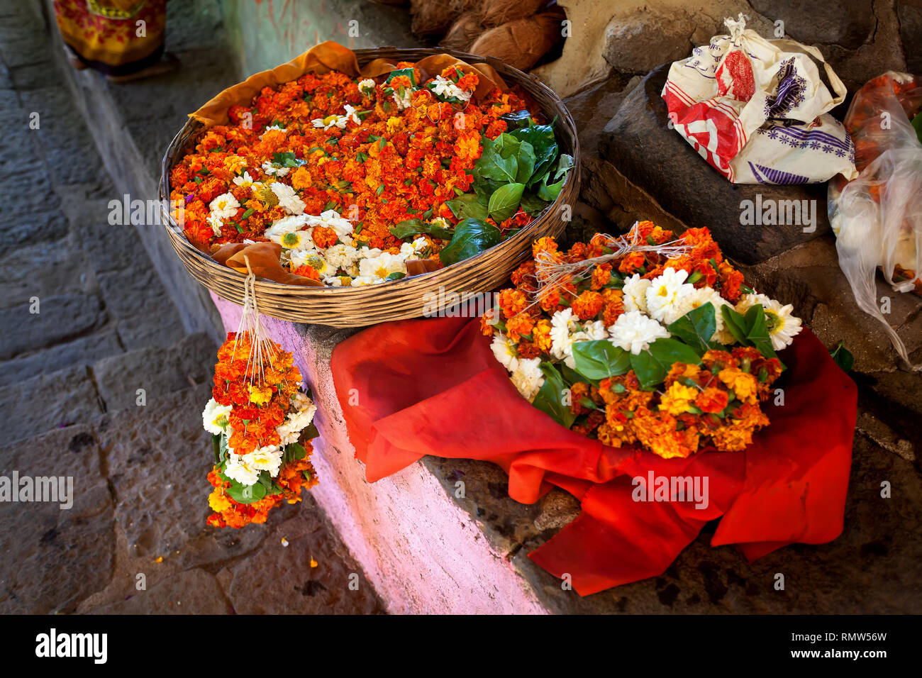 Ghirlanda di fiori di arancio e fiori bianchi nel cestello alla strada del mercato vicino tempio nel Maharashtra, India Foto Stock