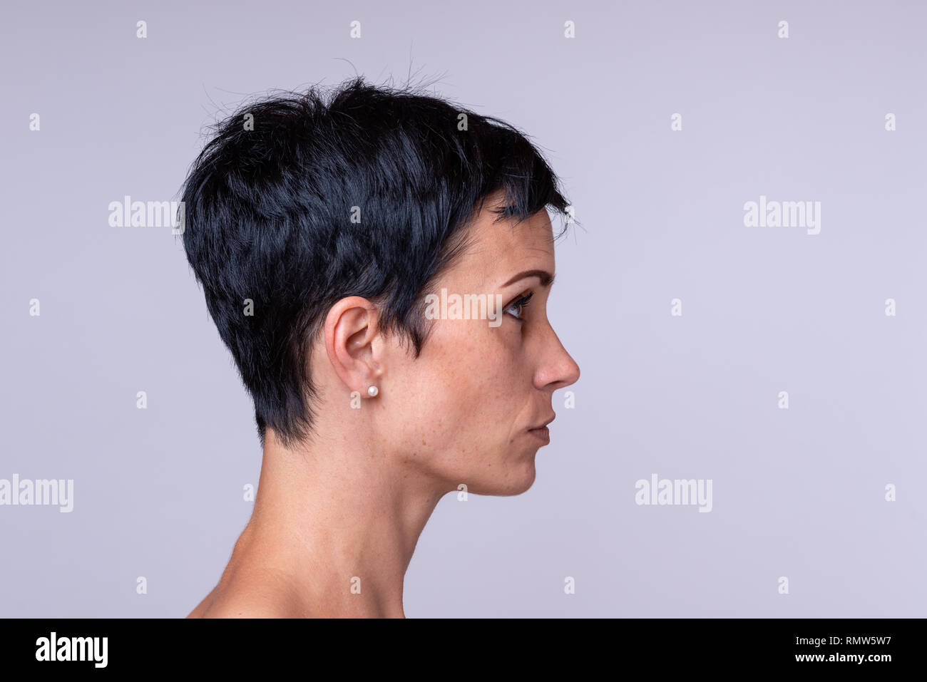 Vista laterale ritratto di una donna in breve capelli scuri su sfondo neutro Foto Stock