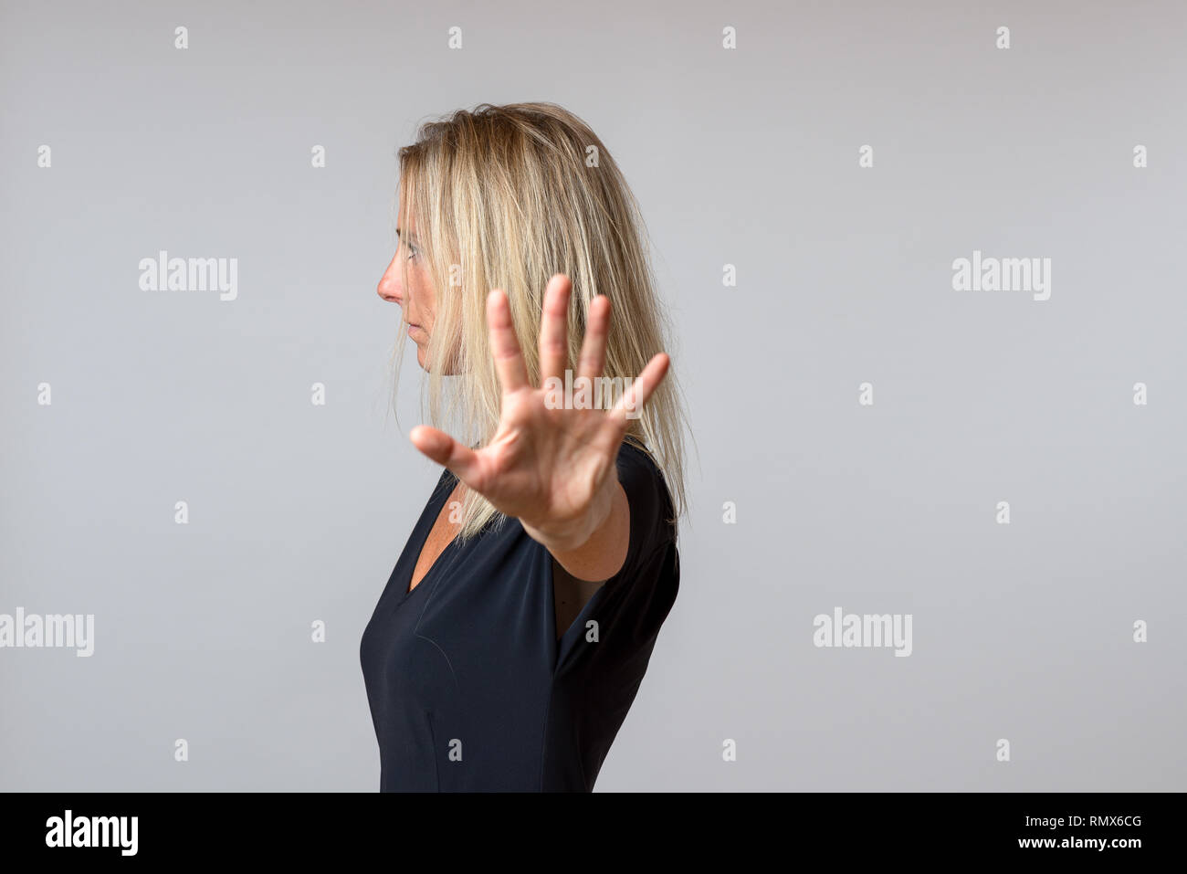 Imperioso arrogante donna gesticolando con la mano in un atteggiamento disfattista mentre si gira a lato Foto Stock