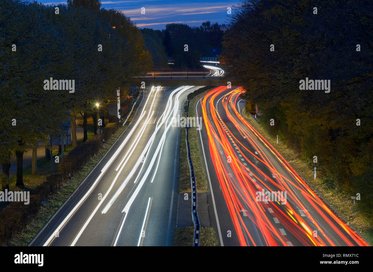 Circolazione su una superstrada di notte in una lunga esposizione con percorsi di luce dei fari e delle luci di coda volger via nella distanza visto fro Foto Stock