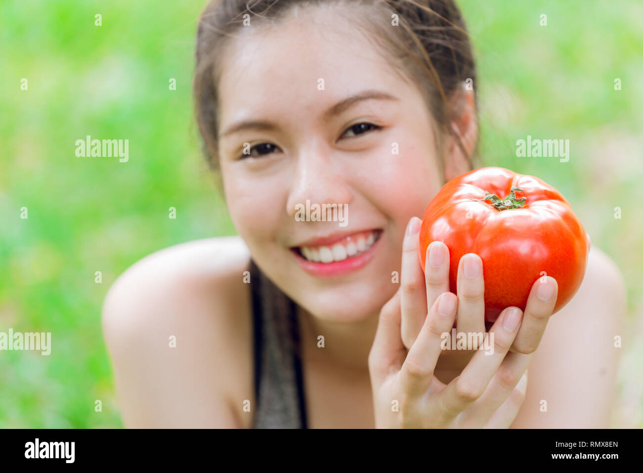 Teen con pomodoro sorriso felice buona pelle sana di mangiare verdura ricca di licopene. Foto Stock