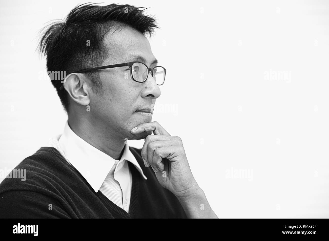 Asian adulto con bicchieri di pensare guardando lontano dalla vista per la visione business man. Foto Stock
