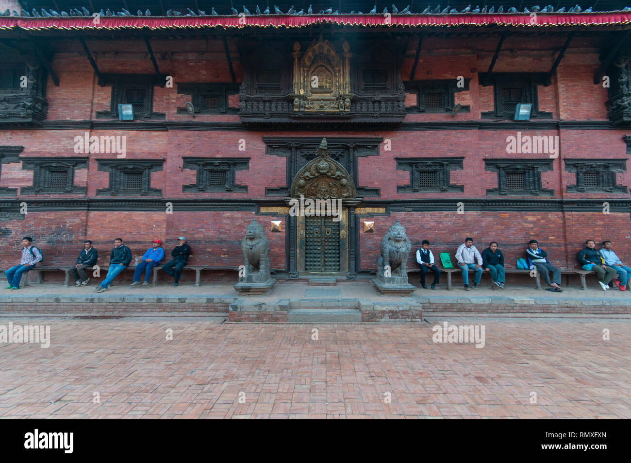 PATAN SQUARE, Kathmandu, Nepal-CIRCA 2013 : Non identificato gli uomini Nepalese sedersi e guardare la gente a piedi da un antico tempio di Patan Square, Nepal. Foto Stock