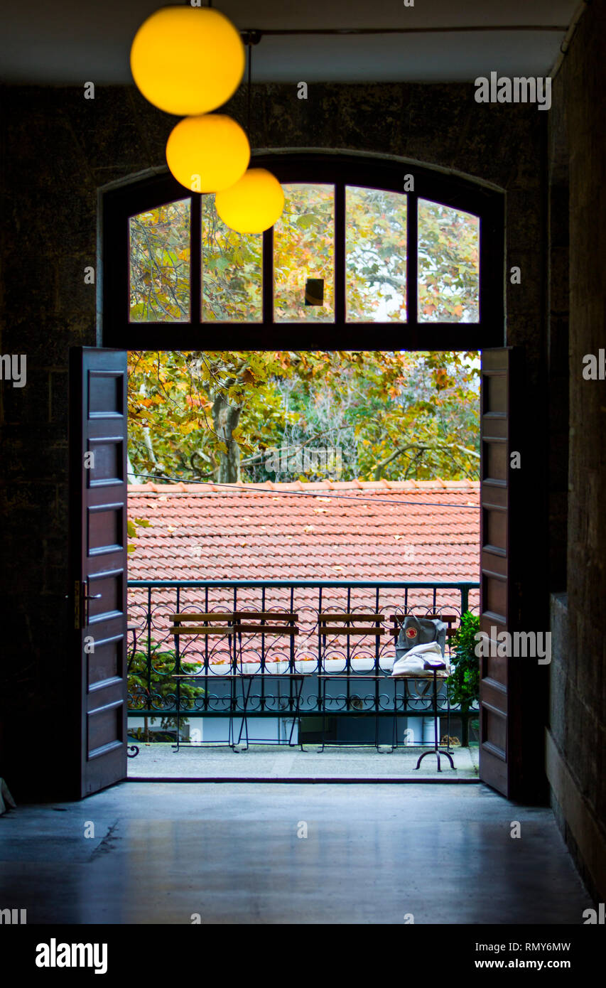 Uno storico edificio in pietra il corridoio con sfera lampade a forma di apertura per un balcone con quattro sedi in attesa per le persone. Foto Stock
