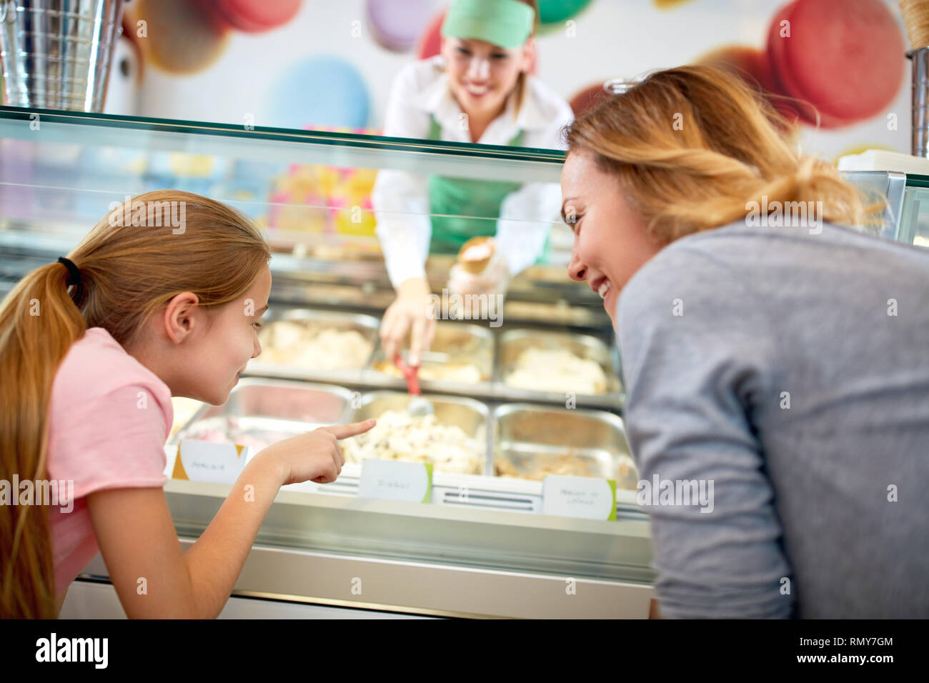 Madre e figlia sceglie il gelato in un colorato negozio di pasticceria Foto Stock