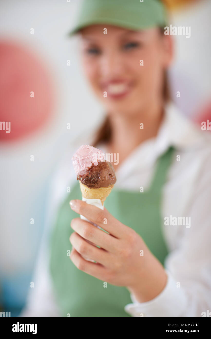 Close up di gelati in cono nella commessa la mano in una pasticceria Foto Stock