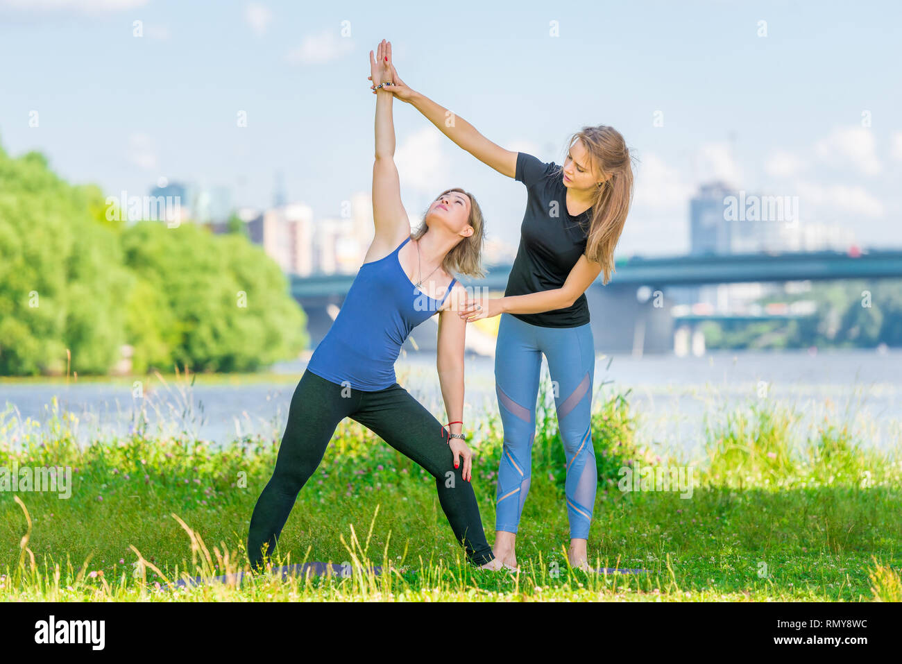 Donna di 40 anni facendo yoga sotto la supervisione di un istruttore nell'aria fresca nel parco in estate Foto Stock