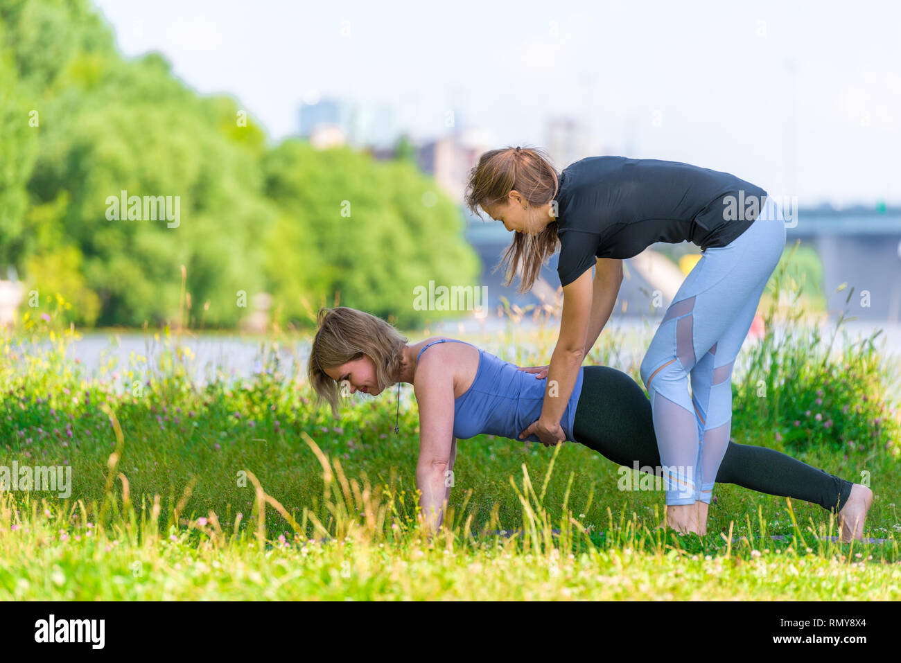 Un allenatore esperto le pratiche yoga su base individuale, sport all'aperto nel parco Foto Stock