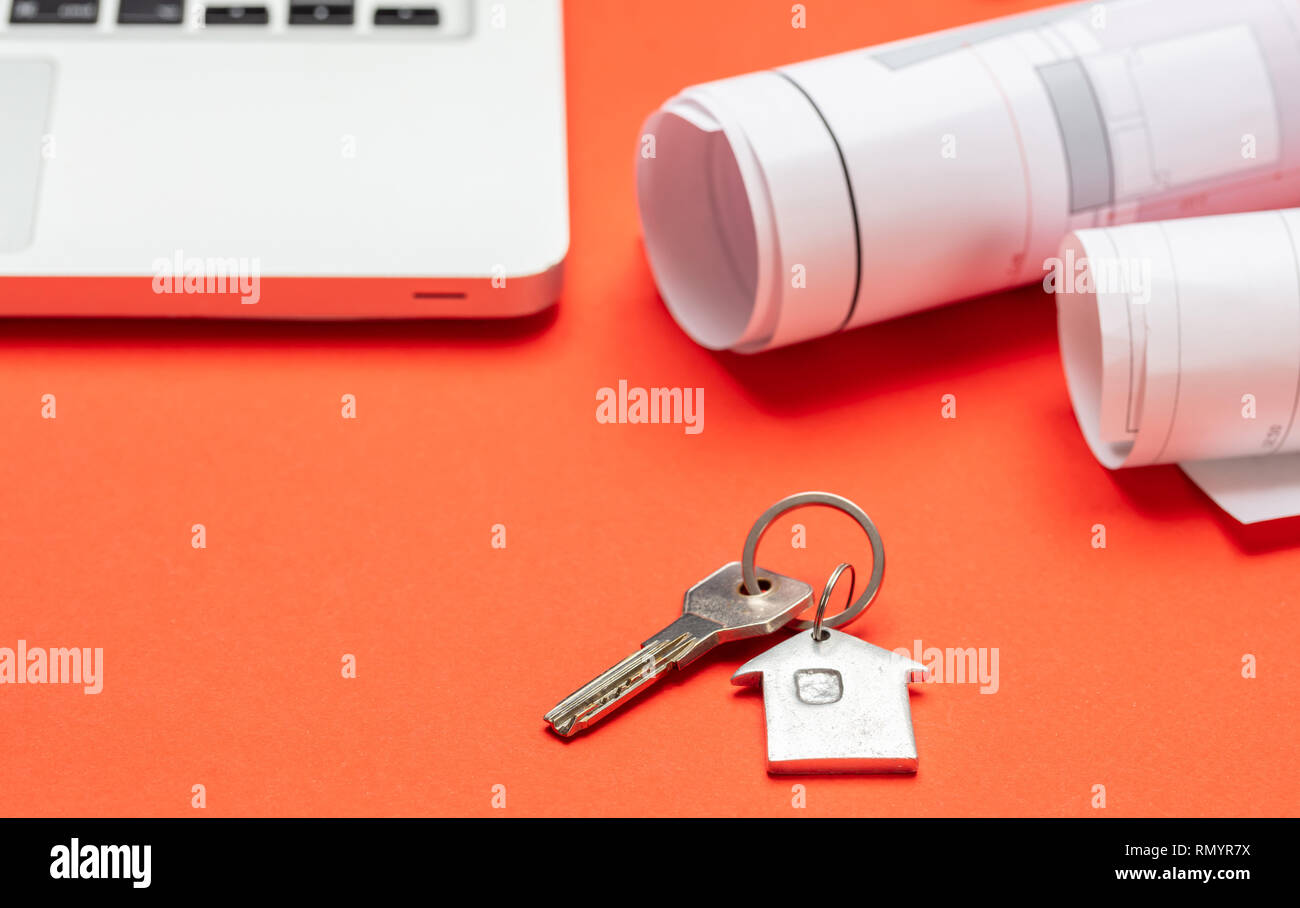 Immobili residenziali, la costruzione di alloggi. Chiave di casa e progetto blueprint sul colore arancione, spazio di copia Foto Stock