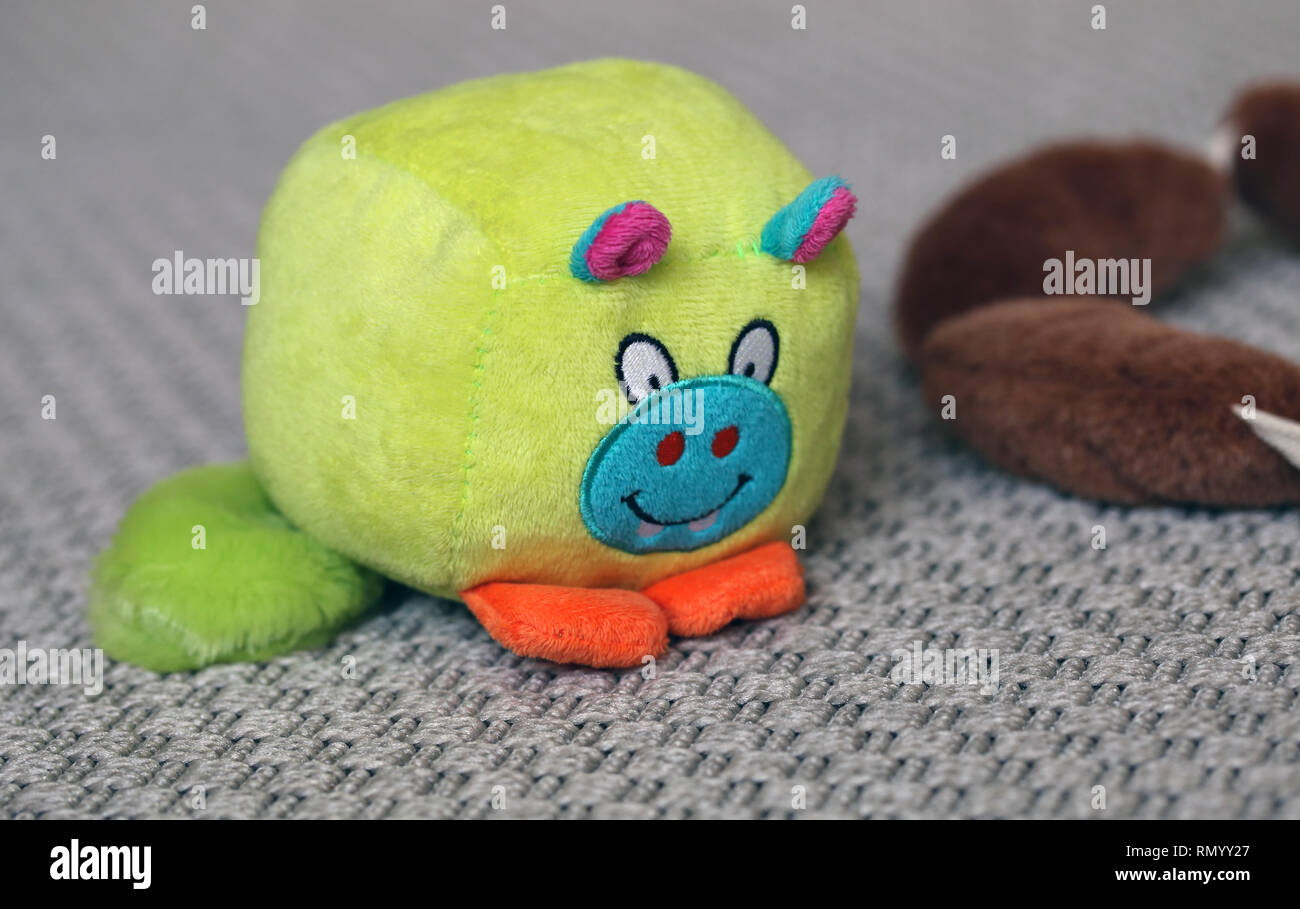 Colorati giocattoli cane su un tappeto grigio. I giocattoli sono marrone ripieni di salsicce e di verde poco monster giocattolo. Carino e giocattoli colorati. Primo piano. Foto Stock