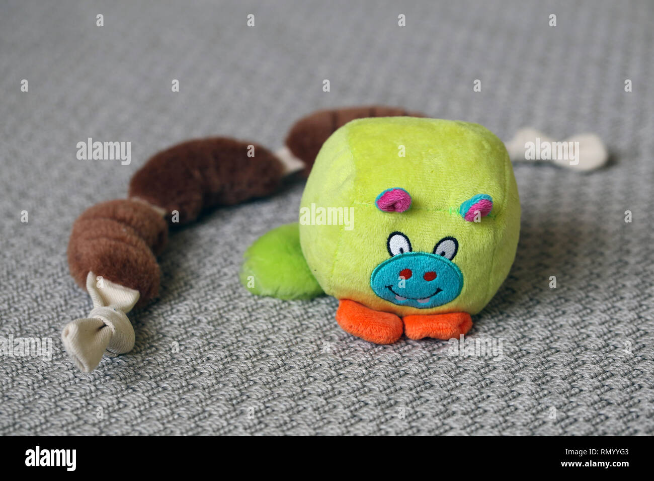Colorati giocattoli cane su un tappeto grigio. I giocattoli sono marrone ripieni di salsicce e di verde poco monster giocattolo. Carino e giocattoli colorati. Primo piano. Foto Stock