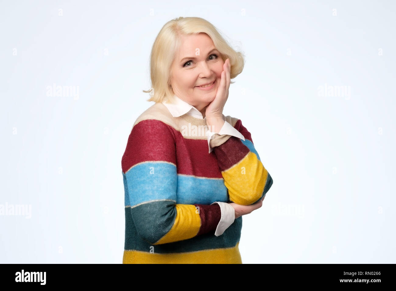 Senior caucasian donna con capelli biondi in felpa colorata sorridente Foto Stock