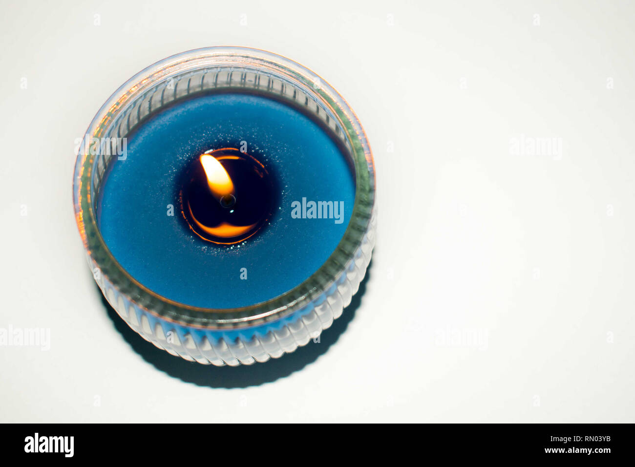 Illuminata candela blu su sfondo bianco Foto Stock