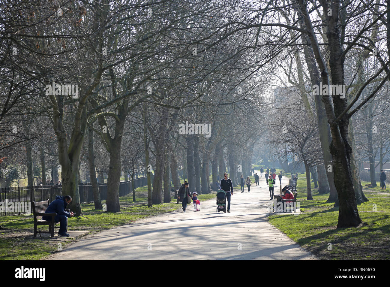 La gente camminare a Holland Park, Londra, su una soleggiata giornata invernale. Mostra i genitori con bambini e cane-walkers. Foto Stock