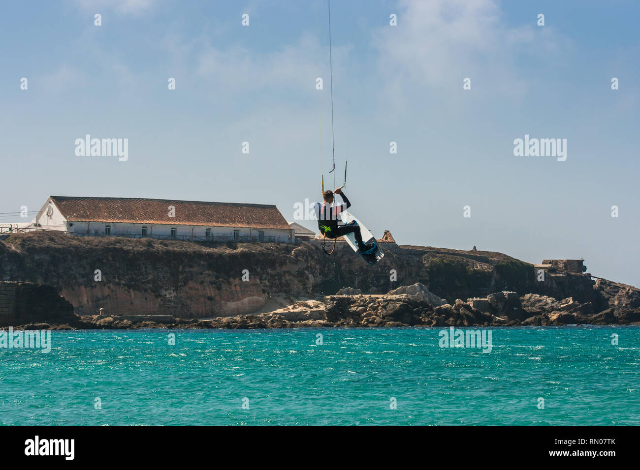 Immagine di un kite surfer di eseguire difficili acrobazie in venti alti. Extrme sport girato a Tarifa, Andalusia, Spagna Foto Stock