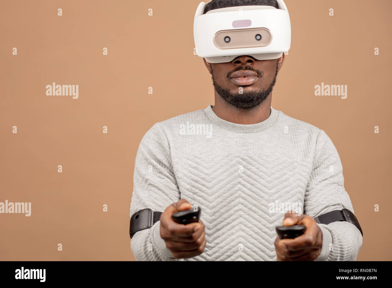 Di carnagione scura millenario il turista in un abbigliamento informale con gli occhiali con testa-display montato per smart phone, operando con i controller in mani, il DOI Foto Stock