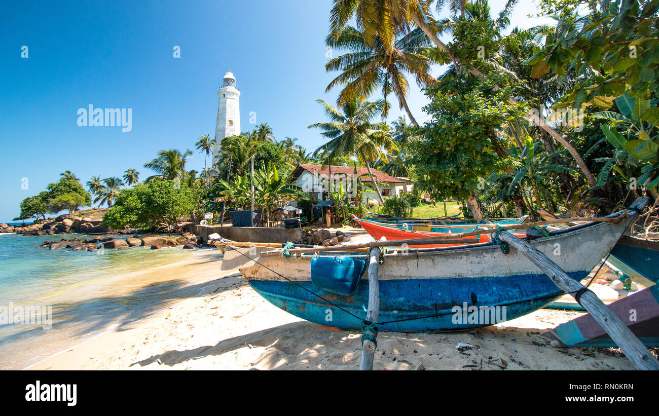 Barca su una spiaggia con un faro in sri lanka Foto Stock