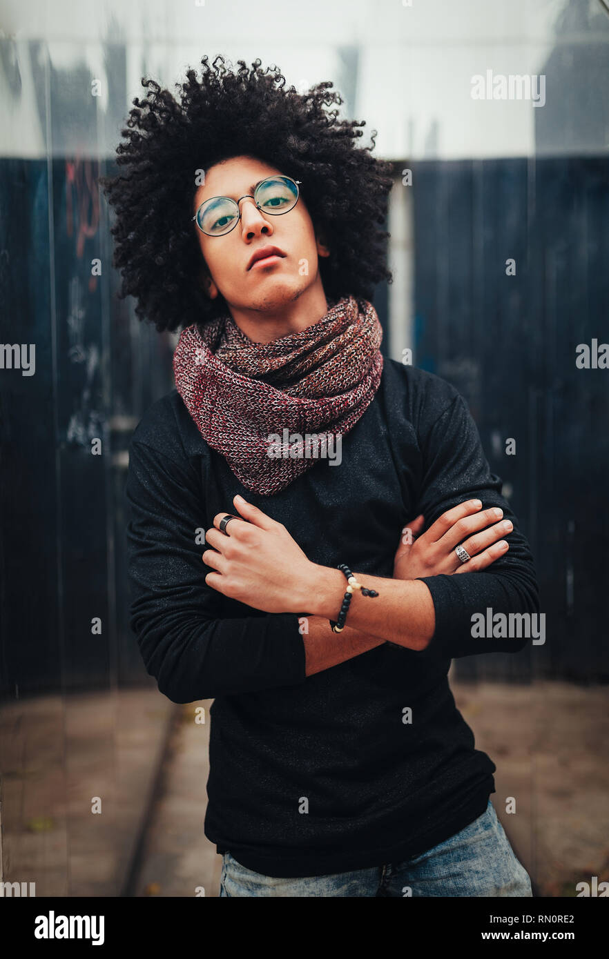 Giovani Afro American giovane imprenditore o studente vestita di nero turtleneck maglione e sciarpa e avente ricci capelli scuri. Concetto di elegante e alla moda Foto Stock