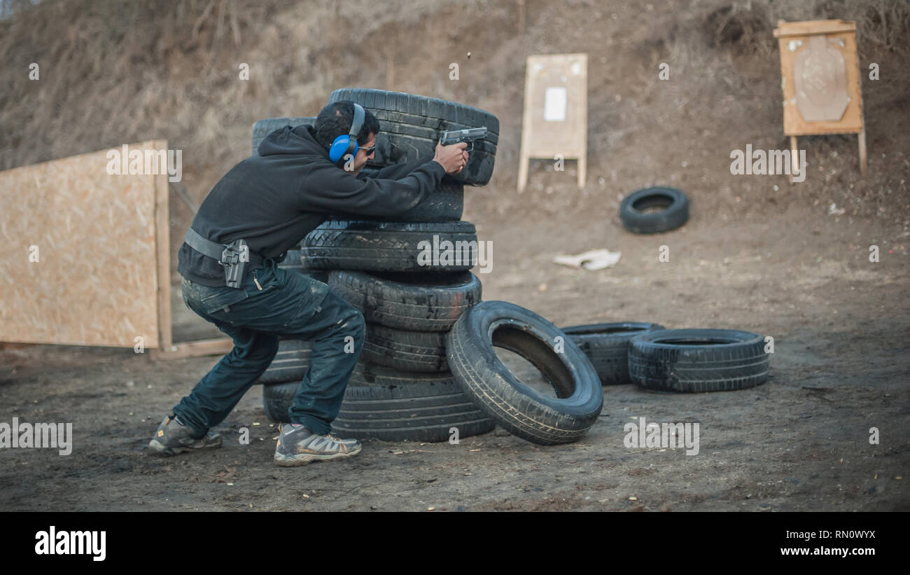 Advanced outdoor di tiro tattico su target intorno alla barriera e la parete. Arma da fuoco civili la formazione in materia di sicurezza sul poligono di tiro Foto Stock