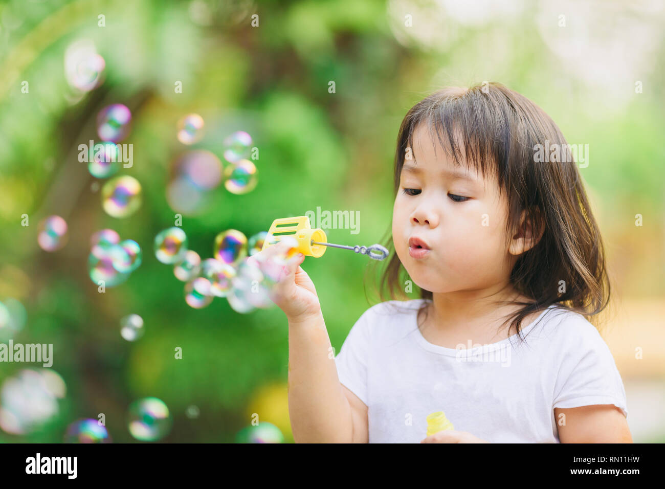 Attività all'aperto : capretto carino soffiare bolle sapone in giardino. Immagine per il concetto di infanzia in età scolastica. Foto Stock