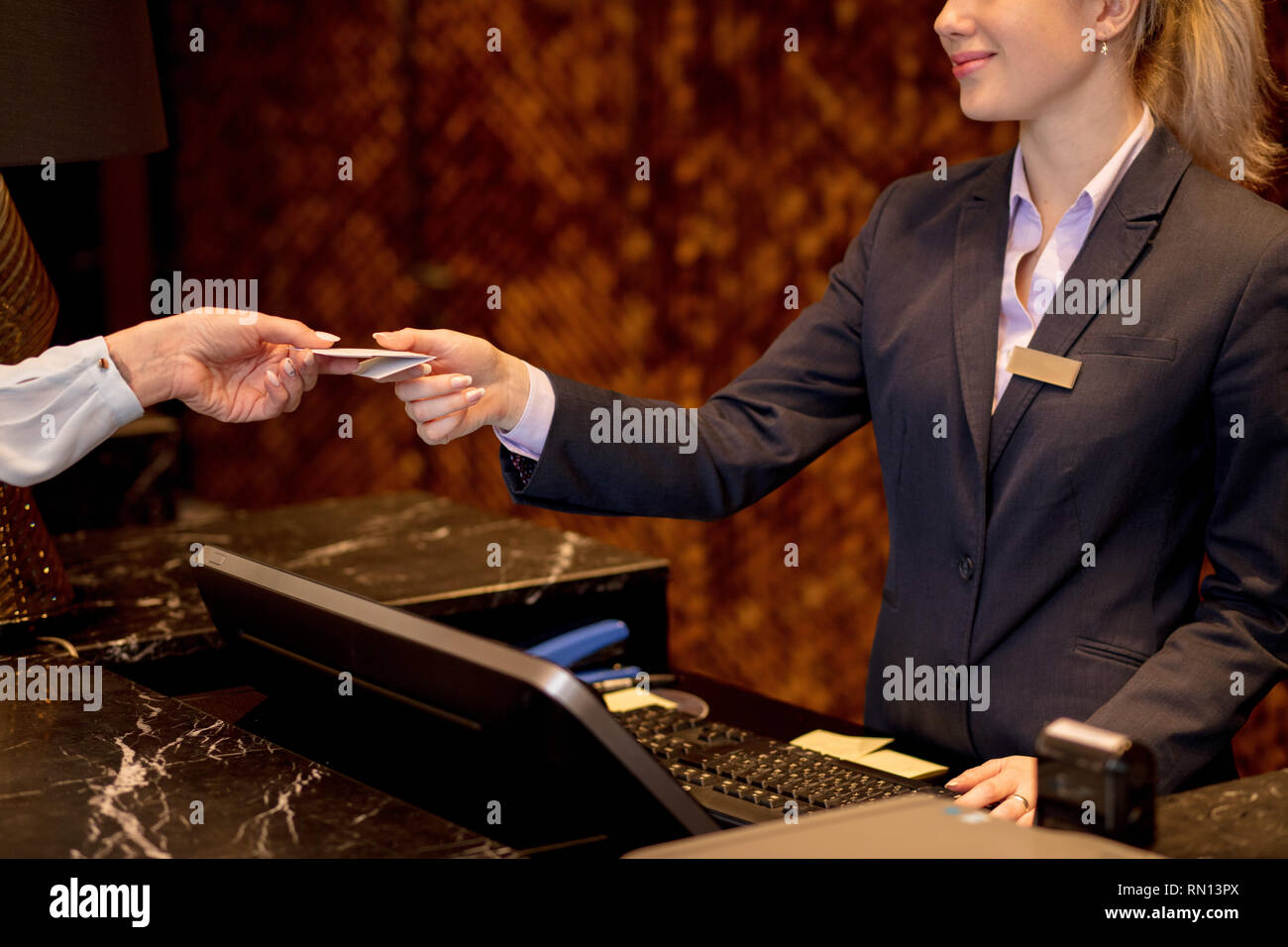 Close up di mani femminili con vuoto badge bianco arrivando in hotel, dà carta di credito per addetta alla ricezione, controllo dell'hotel. Foto Stock