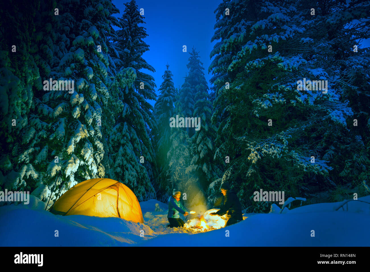 Giovane camping con falò e tenda all'aperto in inverno Foto Stock
