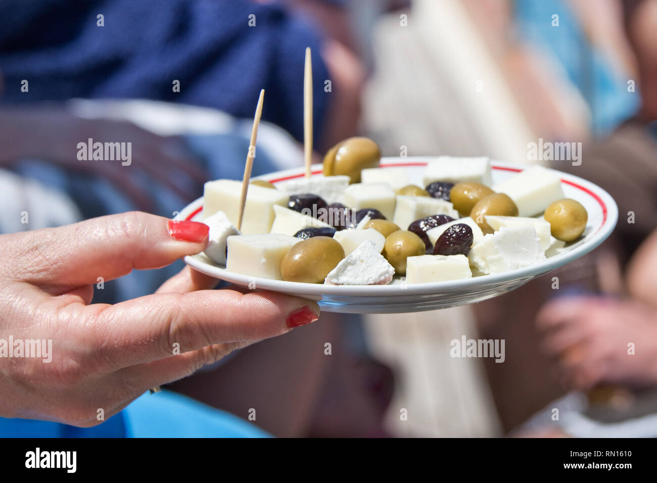 Donna mano che tiene una piastra di olivse e formaggio feta durante una festa estiva Foto Stock