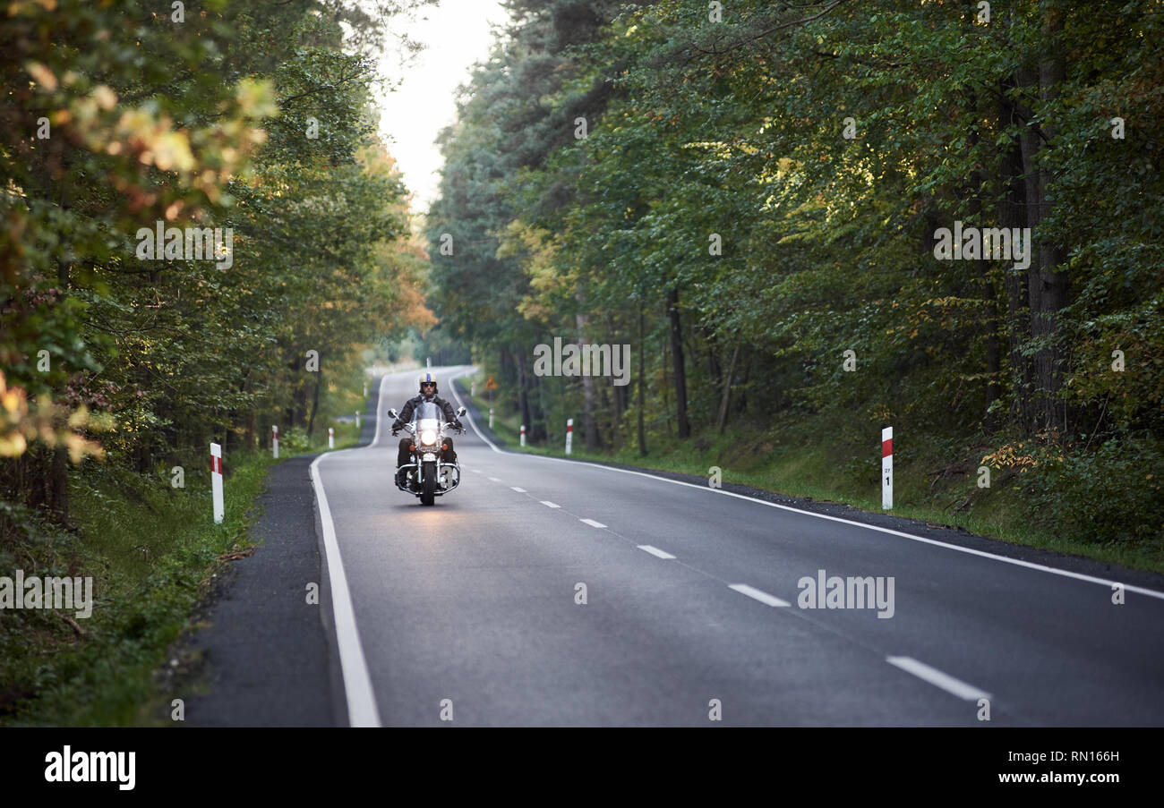 Di motociclisti in casco e pelle nera di equitazione abbigliamento moderno e  potente moto lungo la strada asfaltata avvolgimento tra alti alberi verdi  sulla soleggiata giornata autunnale Foto stock - Alamy
