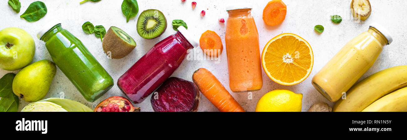 Vari i frullati o succhi di frutta in bottiglie e ingredienti su bianco e una sana dieta vegana detox alimenti puliti concetto, vista dall'alto, banner. Foto Stock